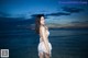 A woman in a white bikini standing in the water.