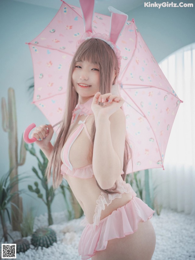 A woman in a pink bikini holding an umbrella.