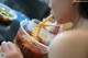 A woman eating noodles with chopsticks in a bowl.