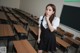 A woman standing in front of a classroom full of desks.