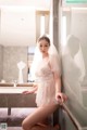 A woman in a white dress sitting on a bathroom counter.