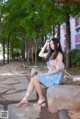 A woman sitting on a stone bench in a park.