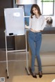 A woman standing in front of a white board with writing on it.