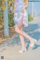 A woman in a pink and blue dress is walking down a sidewalk.