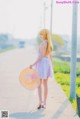 A woman in a white dress and a straw hat walking down a sidewalk.