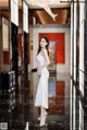 A woman in a white dress standing in a hallway.