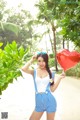 A woman holding a red heart shaped balloon in her hand.