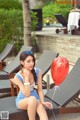 A woman sitting on a lounge chair holding a red balloon.