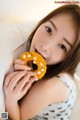 A woman is holding a donut in her mouth.