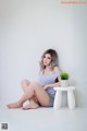 A woman sitting on a white stool next to a plant.