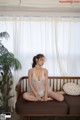 A woman sitting on a couch in a white lingerie.