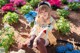 A woman sitting on the ground in front of flowers.