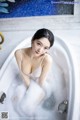 A woman sitting in a bathtub filled with foam.