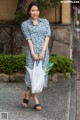 A woman walking down the street carrying a plastic bag.