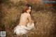 A naked woman sitting in a field of tall grass.