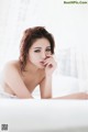 A woman in a white lingerie laying on a bed.