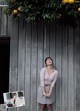 A woman standing in front of a wall with oranges hanging from it.