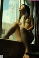 A naked woman sitting on a window sill looking out the window.