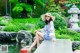 A woman sitting on a stone ledge next to a pond.