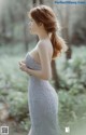 A woman in a wedding dress standing in the woods.