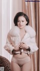 a woman in a white fur coat posing for a picture