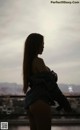 A woman standing on top of a balcony next to a body of water.