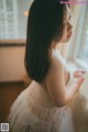 A woman in a white dress looking out a window.