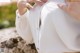 A woman in a white shirt and tan pants sitting on a rock.