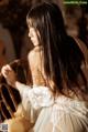 A woman in a white dress sitting on a chair.