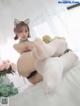 A woman in white stockings and cat ears sitting on a bed.