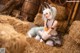 A woman in a bunny costume sitting on a pile of hay.