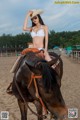 A woman in a bikini sitting on top of a horse.