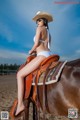 A woman in a white bikini sitting on a brown horse.