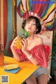 A woman sitting at a table holding a pineapple.