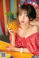 A woman in a red dress holding a pineapple.