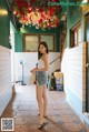 A woman standing in a hallway with flowers hanging from the ceiling.