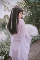 A woman in a white kimono standing on a wooden deck.