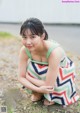 A woman in a colorful dress sitting on the ground.