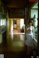 A woman in a white dress standing in a hallway.