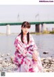 A woman sitting on a rock by the water.