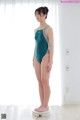 A woman in a green swimsuit standing on a scale.