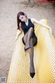 A woman in a black dress sitting on a yellow bench.