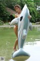 A woman standing in the water holding an inflatable shark.