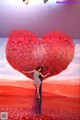 A woman standing in front of a large heart made of roses.