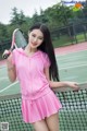 A woman in a pink dress holding a tennis racket.