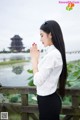 A woman standing on a wooden bridge with her hands clasped in prayer.