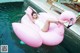 A woman laying on a pink flamingo floating in a pool.