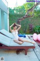 A woman in a white bathing suit sitting on a lounge chair.